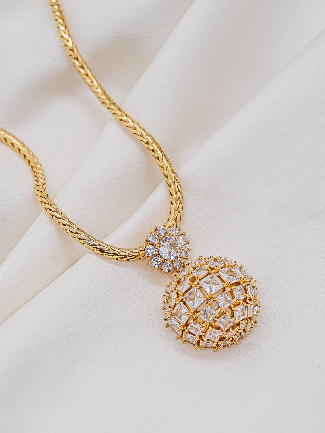 Collier doré à pendentif demi-sphère de zircons carrés, surmonté d’une petite fleur de pierres claires