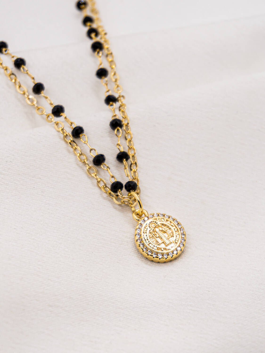 Collier double doré à petits cristaux noirs facettés et médaille de Saint Benoît bordée de pierres