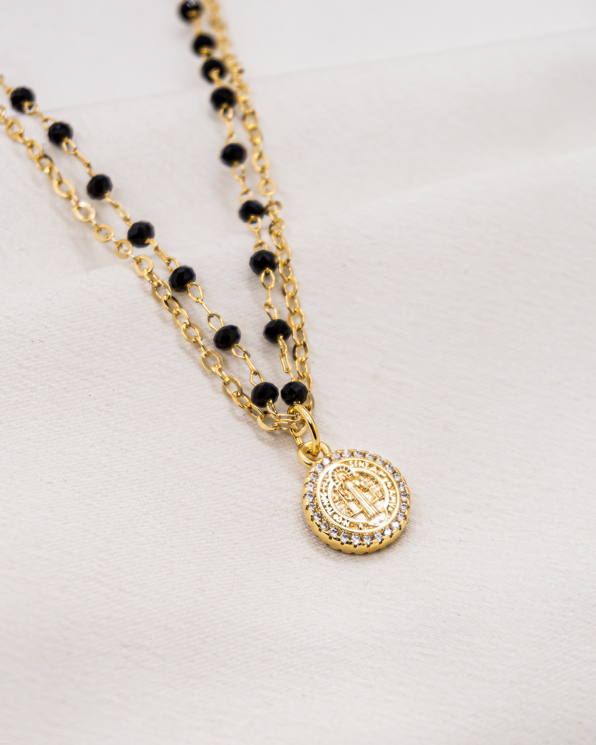 Collier double doré à petits cristaux noirs facettés et médaille de Saint Benoît bordée de pierres