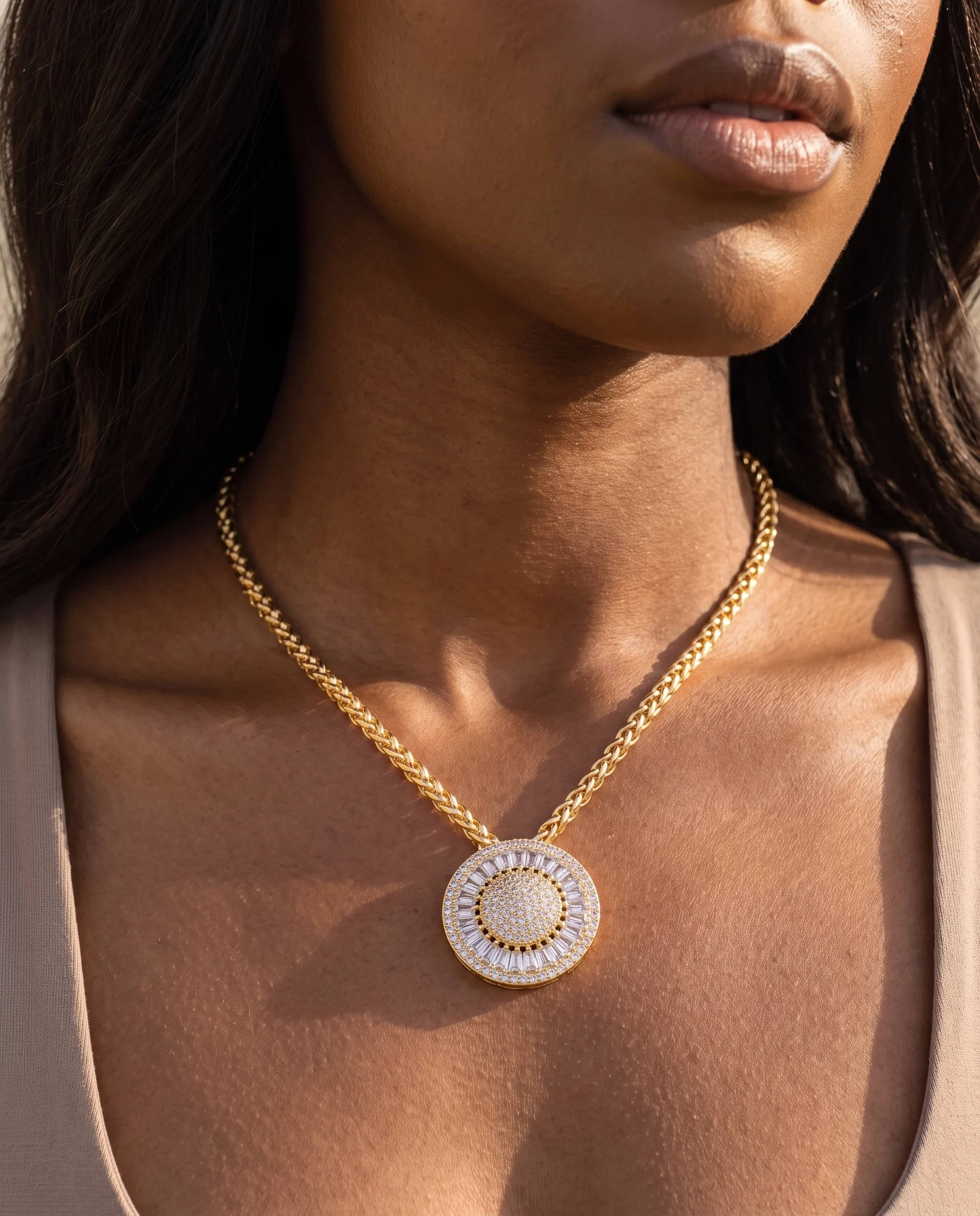 Collier doré à large pendentif rond serti de pierres claires, vu de près