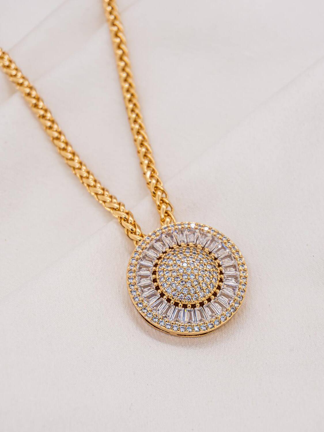 Collier doré à maille tressée, large pendentif rond serti de pierres claires et de baguettes