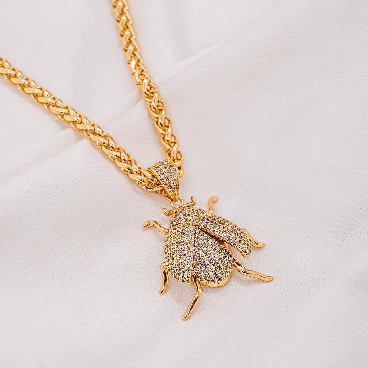 Gold necklace with thick intertwined chain and beetle pendant with pavé-set wings