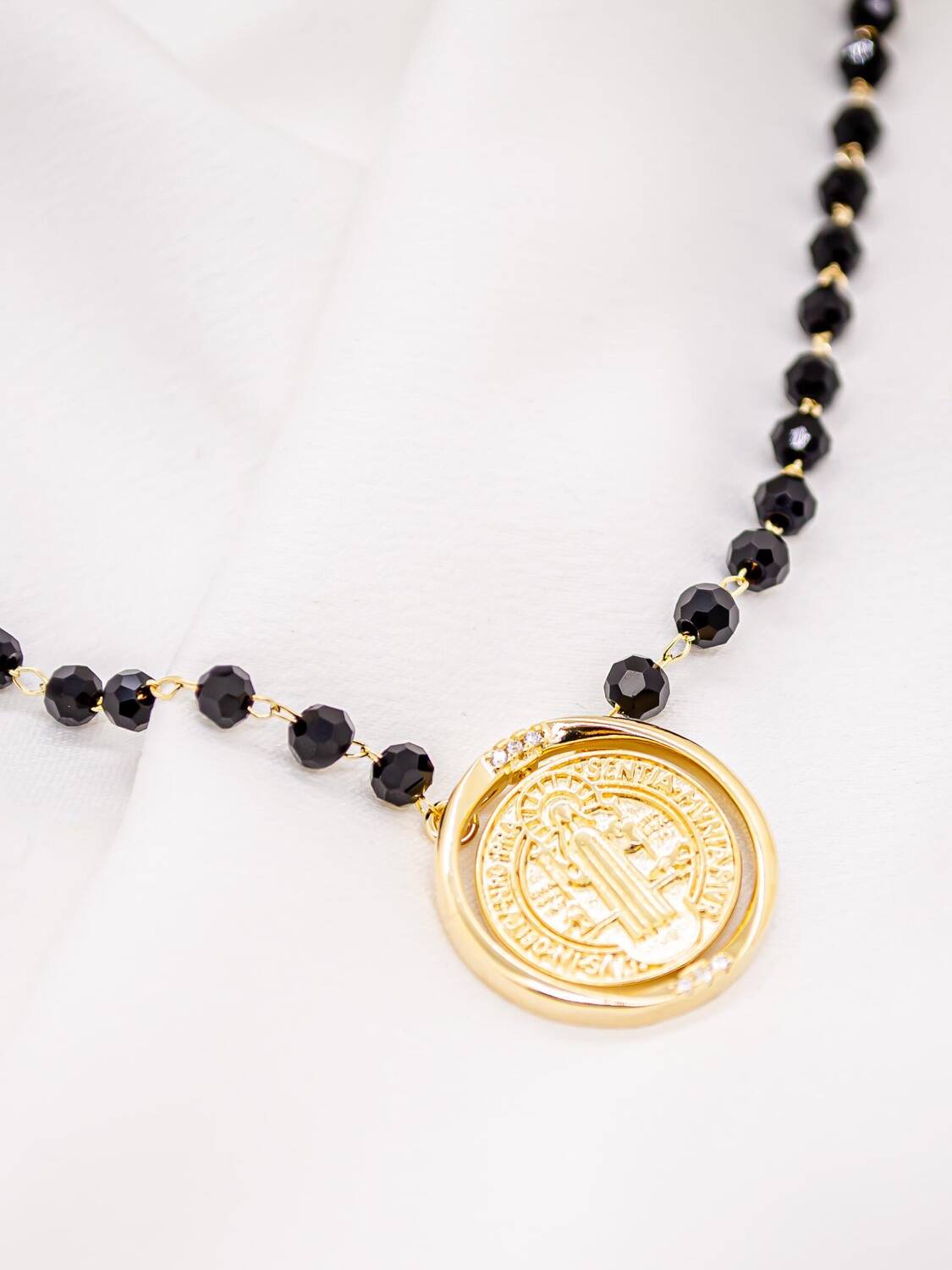 Long collier de cristaux noirs facettés et médaille de Saint Benoît dorée dans un anneau