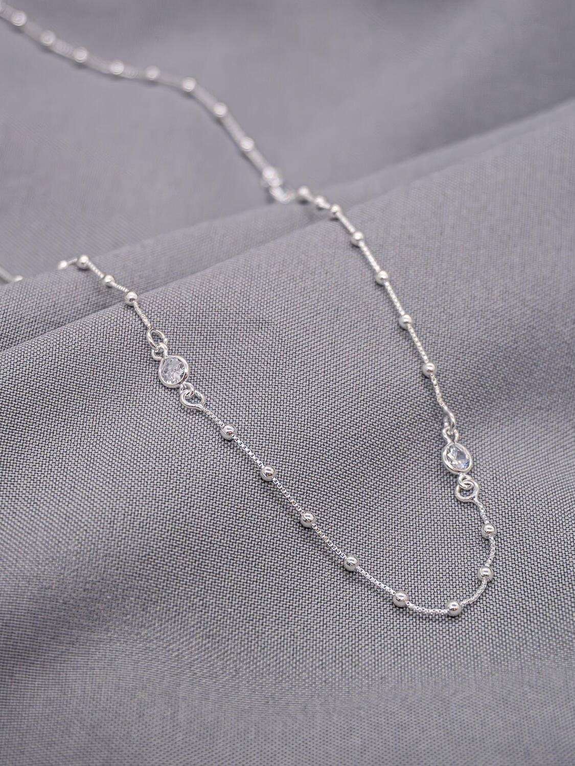 Long collier argenté en chaîne fine à minuscules boules, avec deux maillons sertis d’une pierre claire