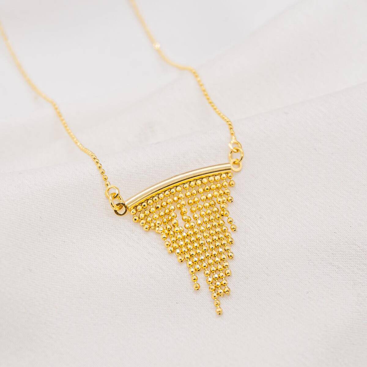 Gold necklace, curved bar with cascading fringe of tiny beads, on fine chain