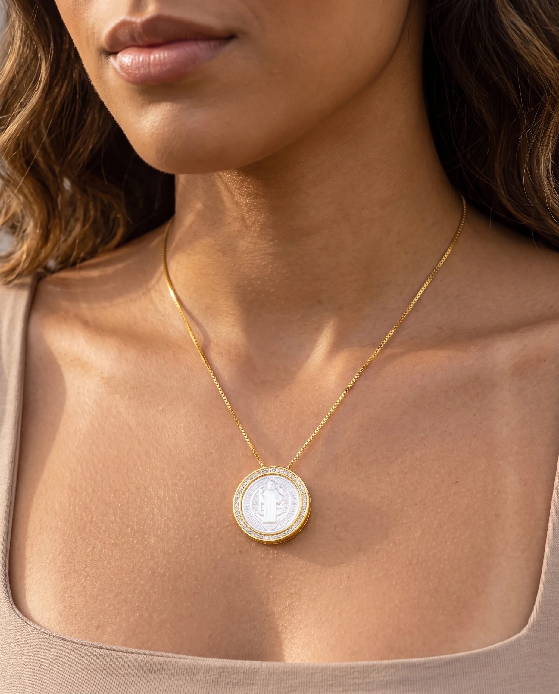 Collier doré à médaille ronde de saint Benoît en nacre, bord serti, porté sur la poitrine, vu de près