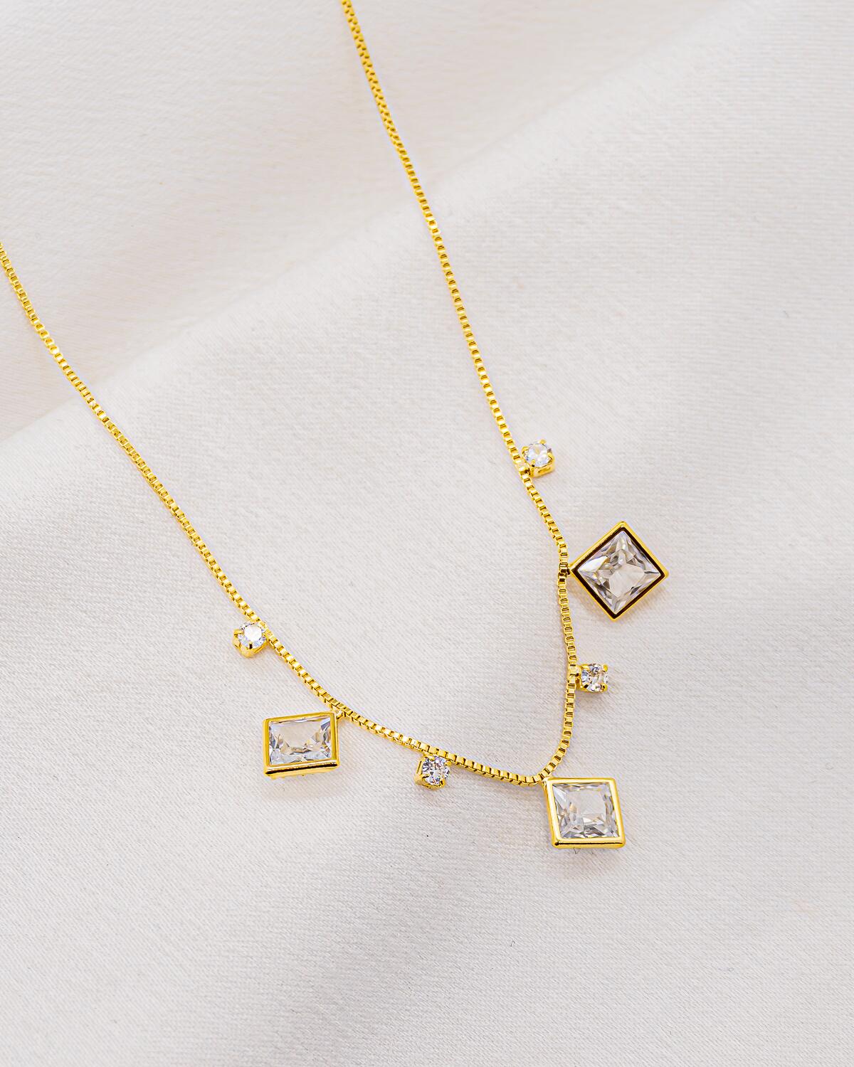 Colar dourado com fina corrente veneziana e grandes zircônias quadradas, pequenas pedras redondas intercaladas