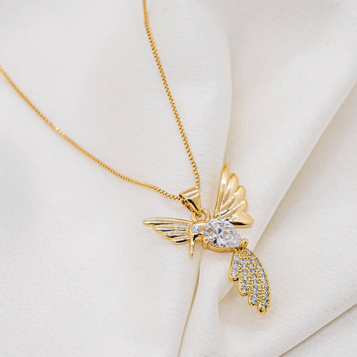 Gold-toned necklace with fine chain and wings-spread hummingbird pendant, clear teardrop stone