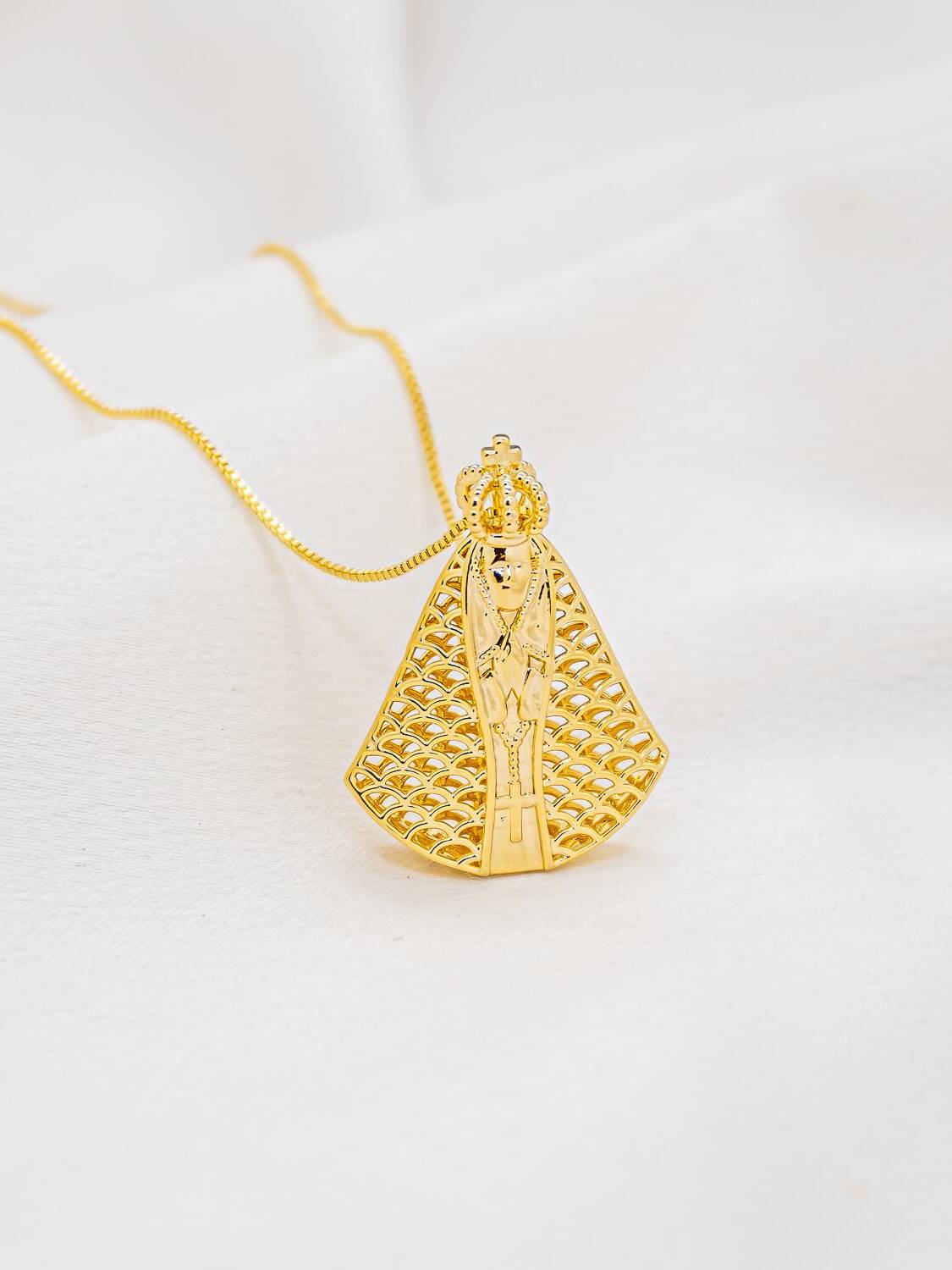 Collier doré à grand pendentif en forme de Vierge couronnée, manteau ajouré en écailles