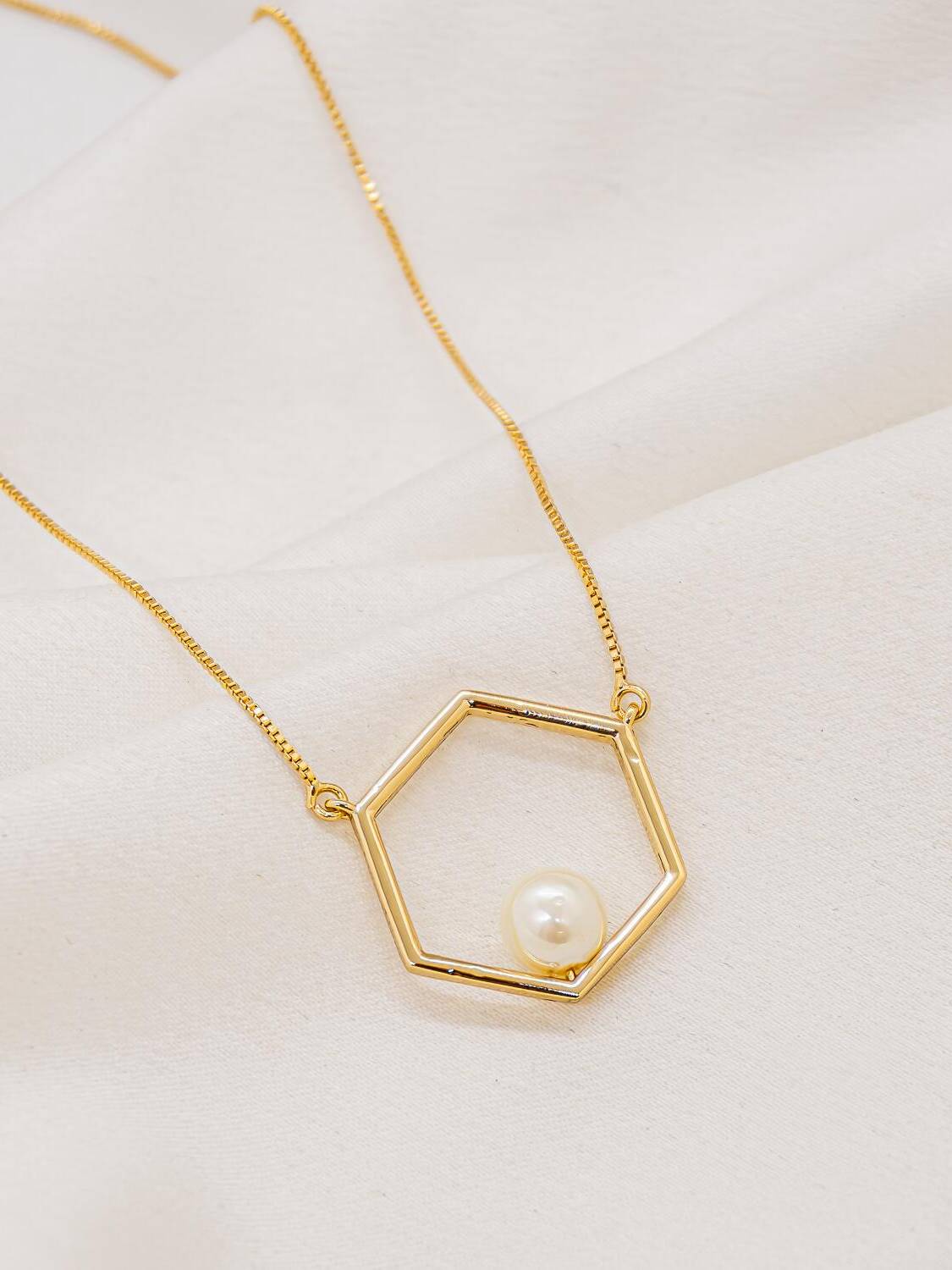 Collier doré à fine chaîne vénitienne, pendentif hexagone ajouré avec une perle blanche dans l’angle