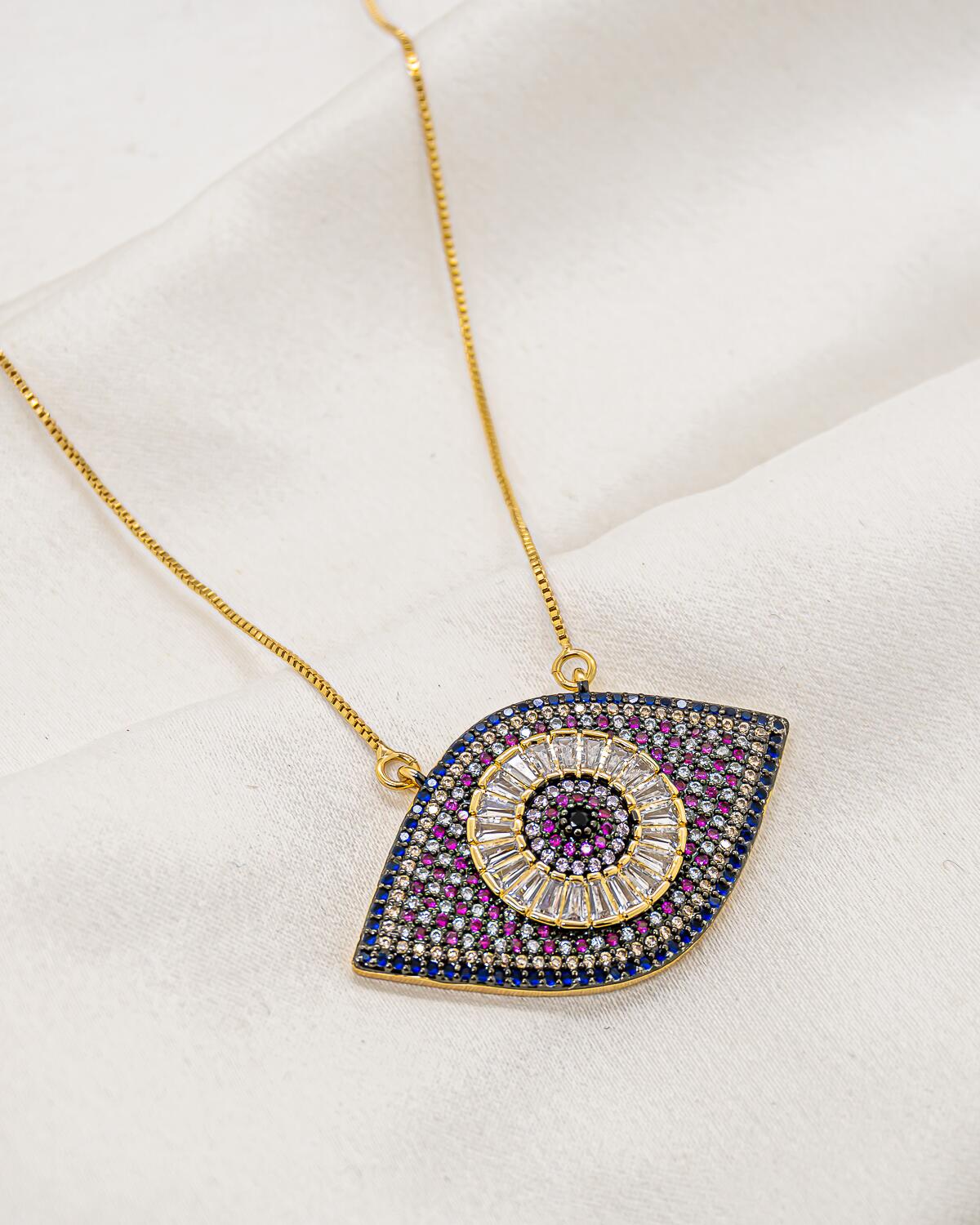 Collier doré à grand pendentif œil grec serti de pierres bleues, roses et claires