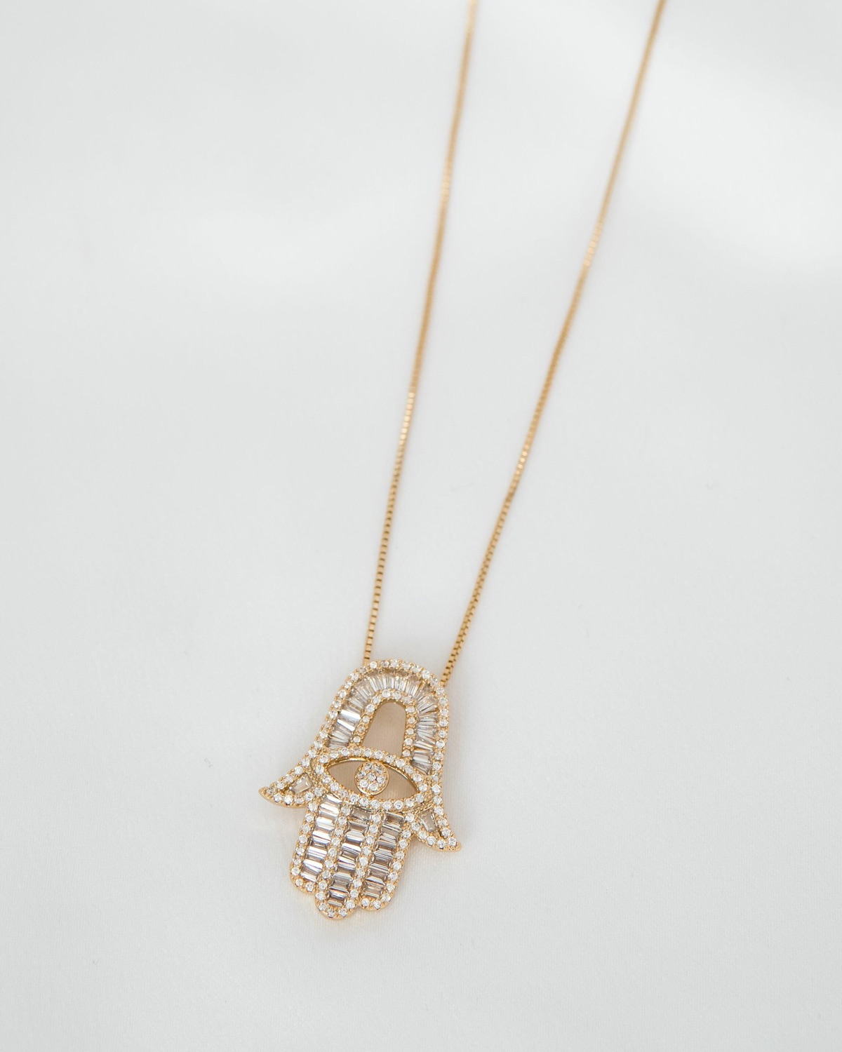 Pendentif main de Fatima ajouré orné de pierres claires baguettes et rondes, sur fine chaîne dorée
