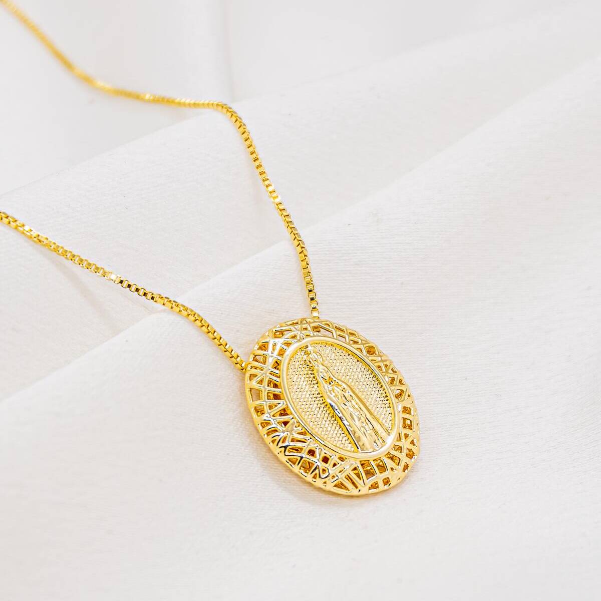 Gold necklace with oval pendant featuring a raised silhouette, surrounded by a filigree frame