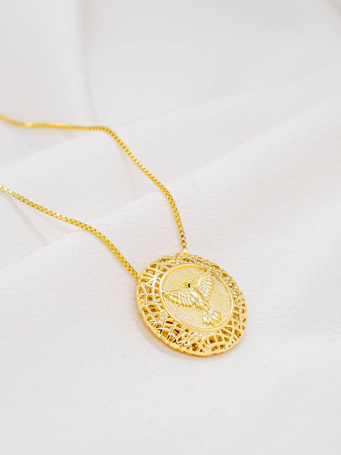 Collier doré à médaillon orné d’une colombe aux ailes déployées dans un cadre filigrané