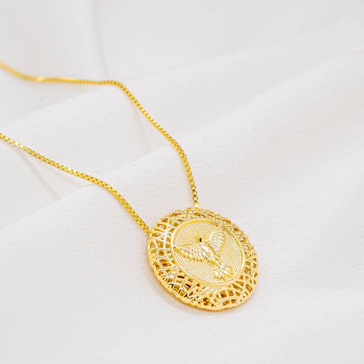 Golden necklace with ornate dove medallion in a filigree frame