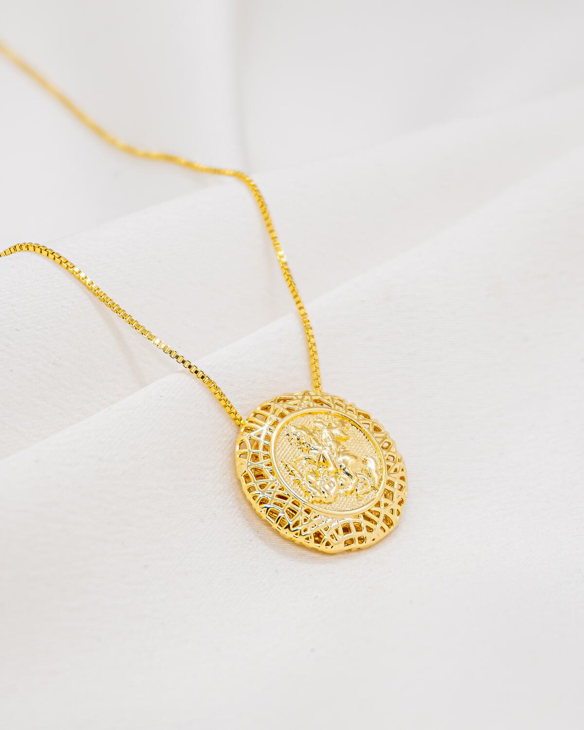 Collier doré à médaillon rond montrant un cavalier à la lance en relief, cadre filigrané