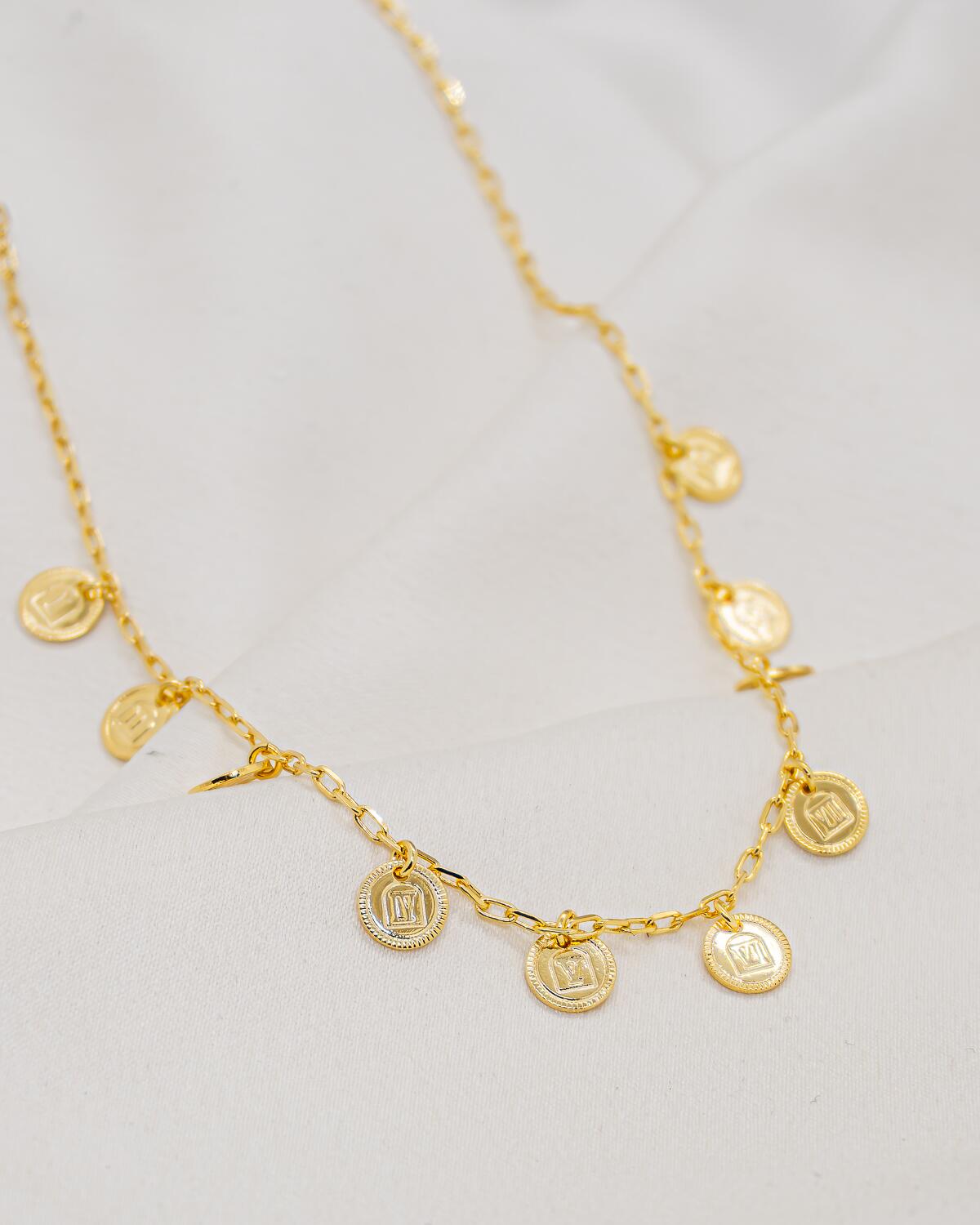Collier doré à maillons allongés, orné de petites médailles rondes au motif carré