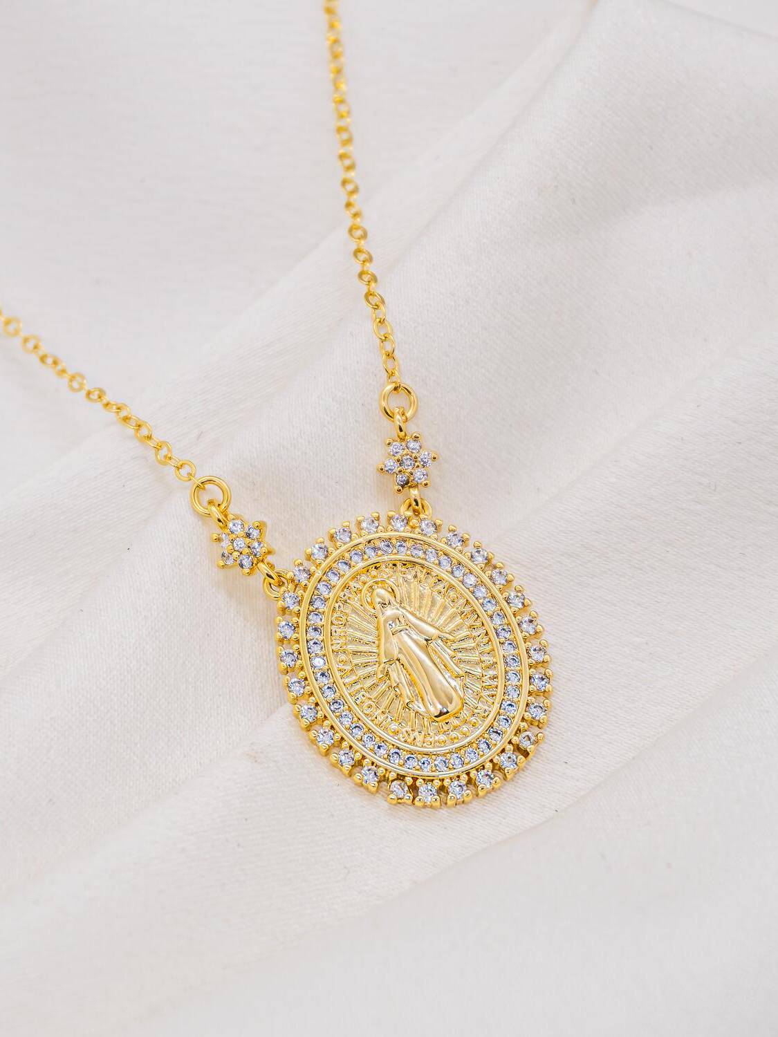 Collier doré à médaille ovale de la Vierge, bordure de pierres claires et deux fleurs serties