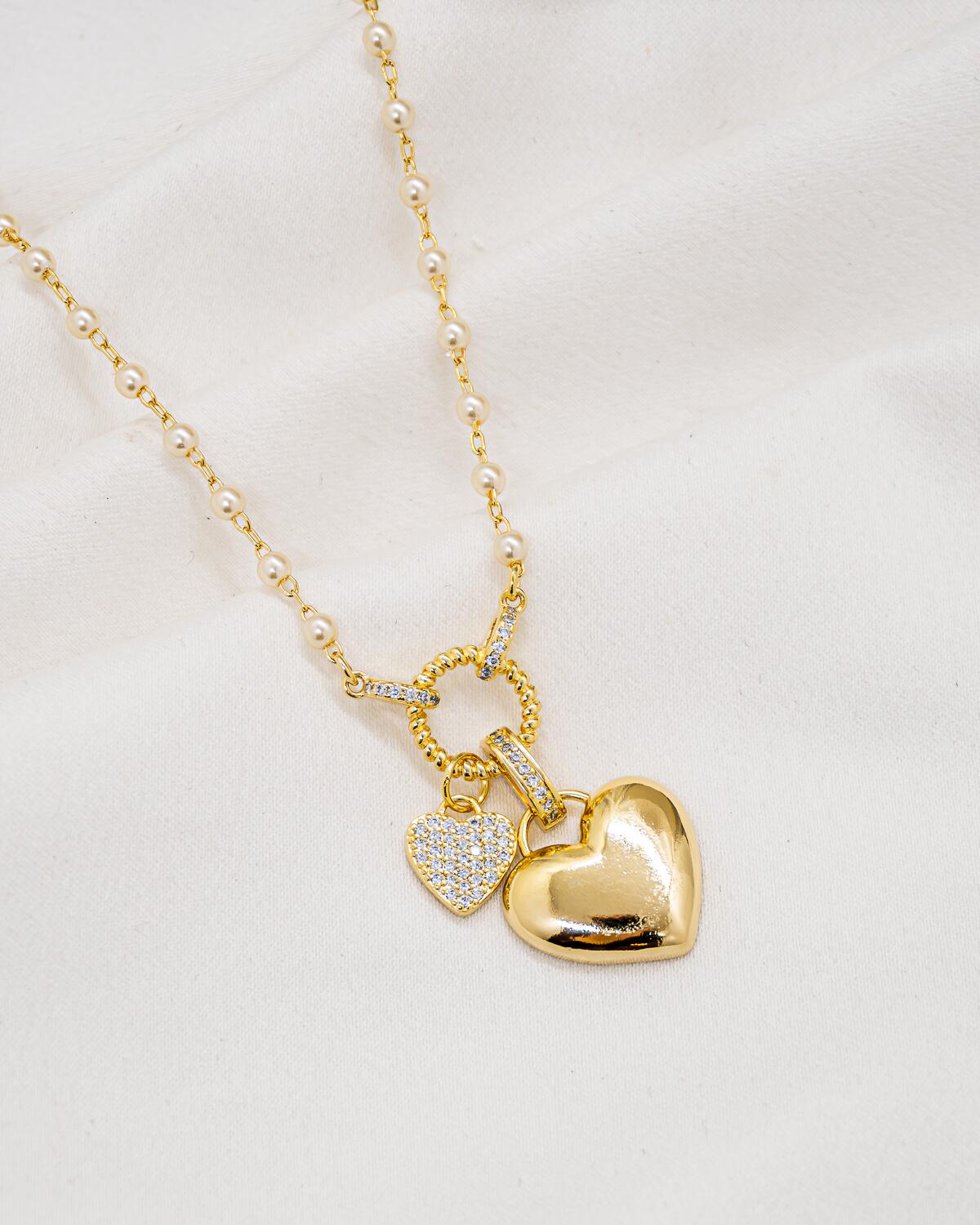 Collier doré à petites perles blanches, anneau torsadé et deux cœurs, l’un lisse, l’autre serti