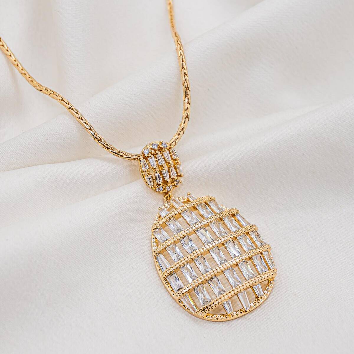Gold necklace with long openwork oval pendant, baguette zircon rows, and pavé-set bail