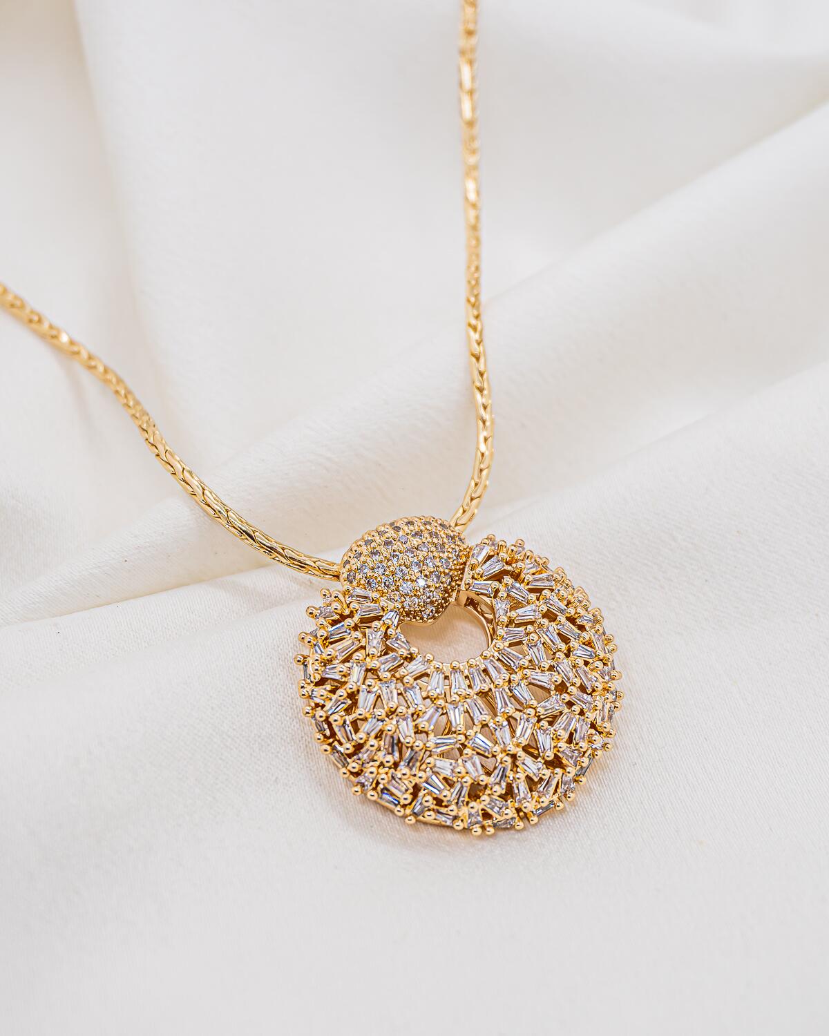Collier doré à large pendentif rond ajouré couvert de zircons baguette, bélière en dôme sertie