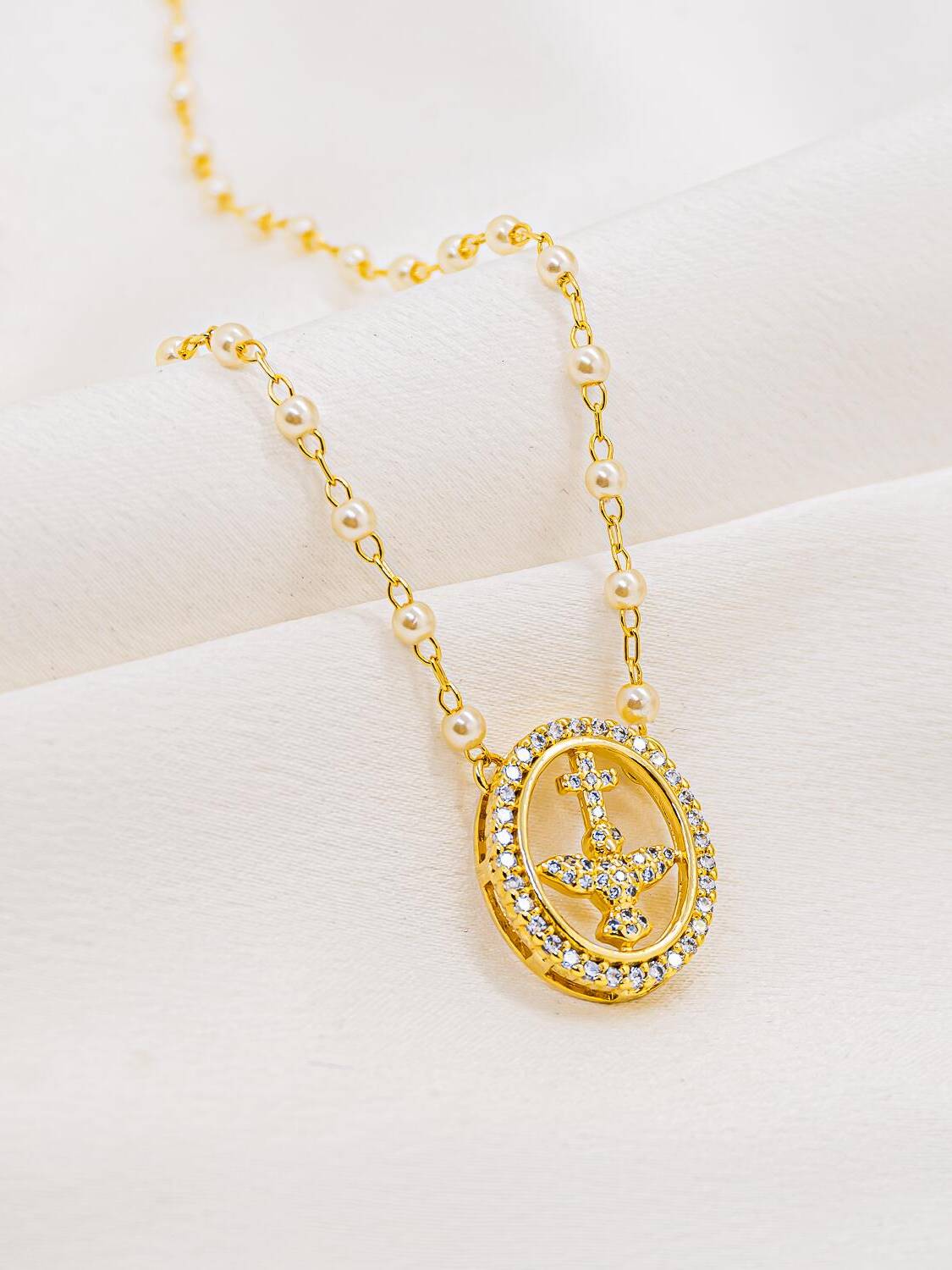 Collier de petites perles blanches et maillons dorés, médaille ovale sertie avec colombe et croix