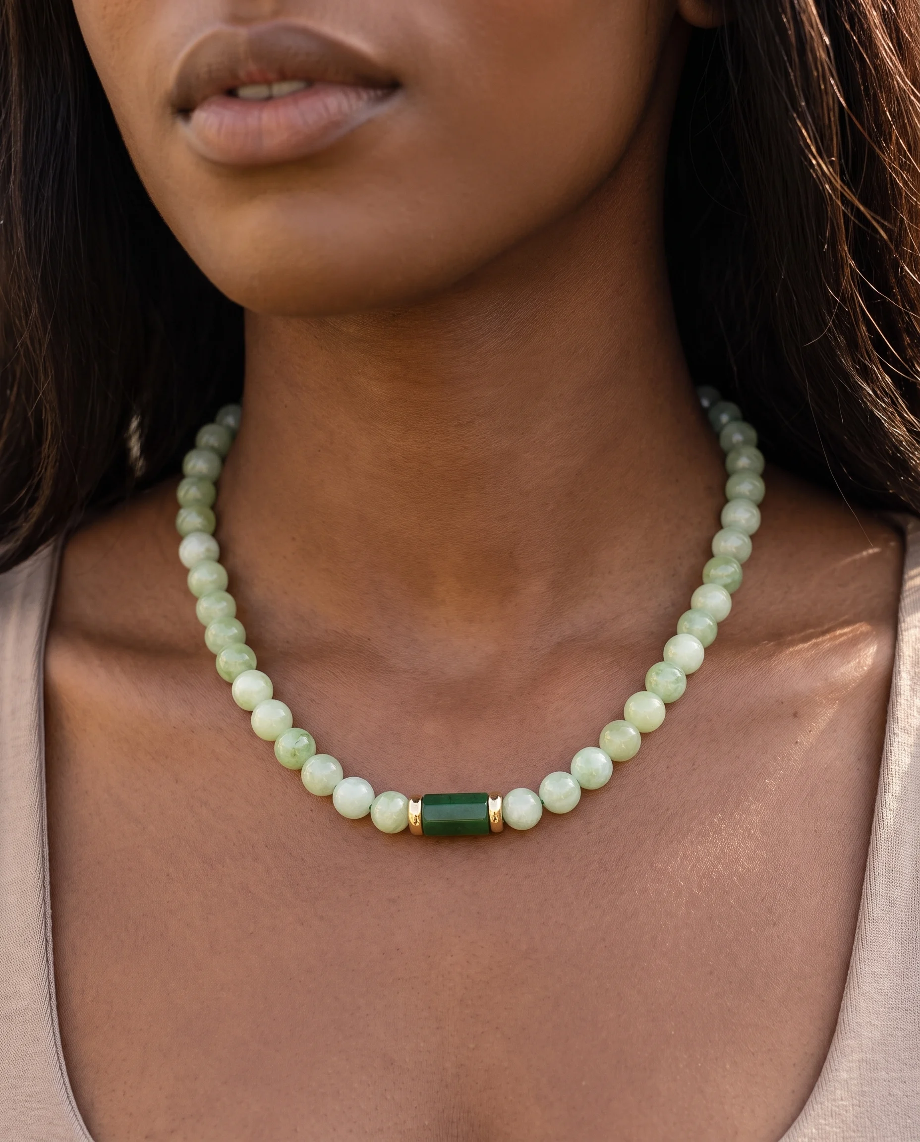 Collier de perles d'agate vert pâle à pierre centrale vert foncé, porté sur les clavicules, vu de près
