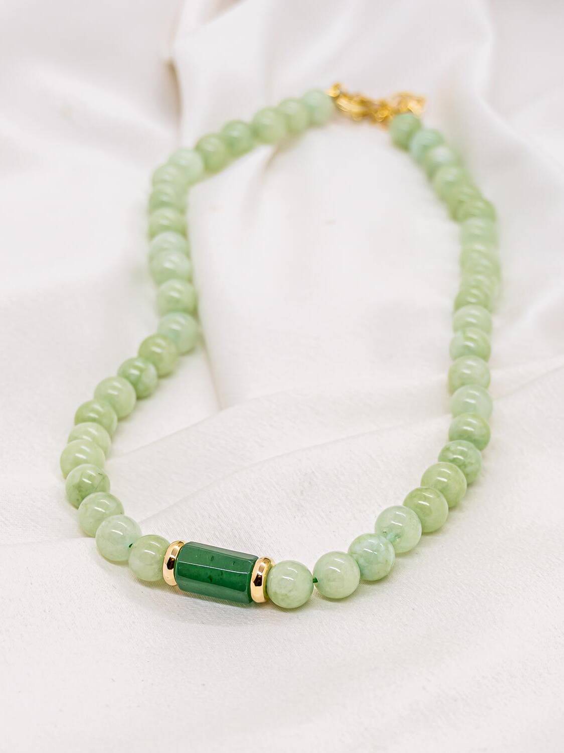 Collier de perles rondes en pierre verte avec pièce centrale cylindrique vert foncé et bagues dorées