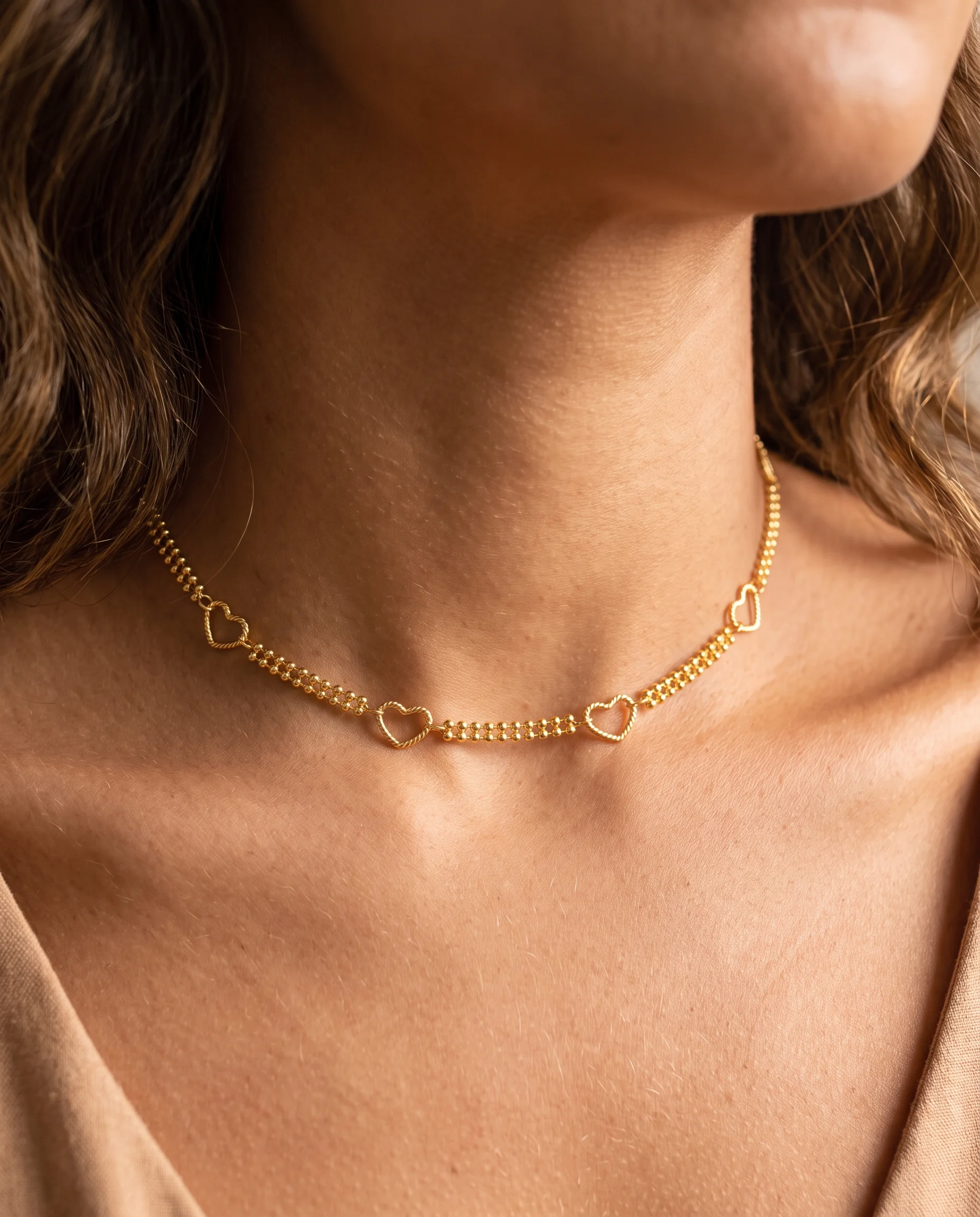 Gold-plated choker with double-strand beads and textured openwork hearts, close-up