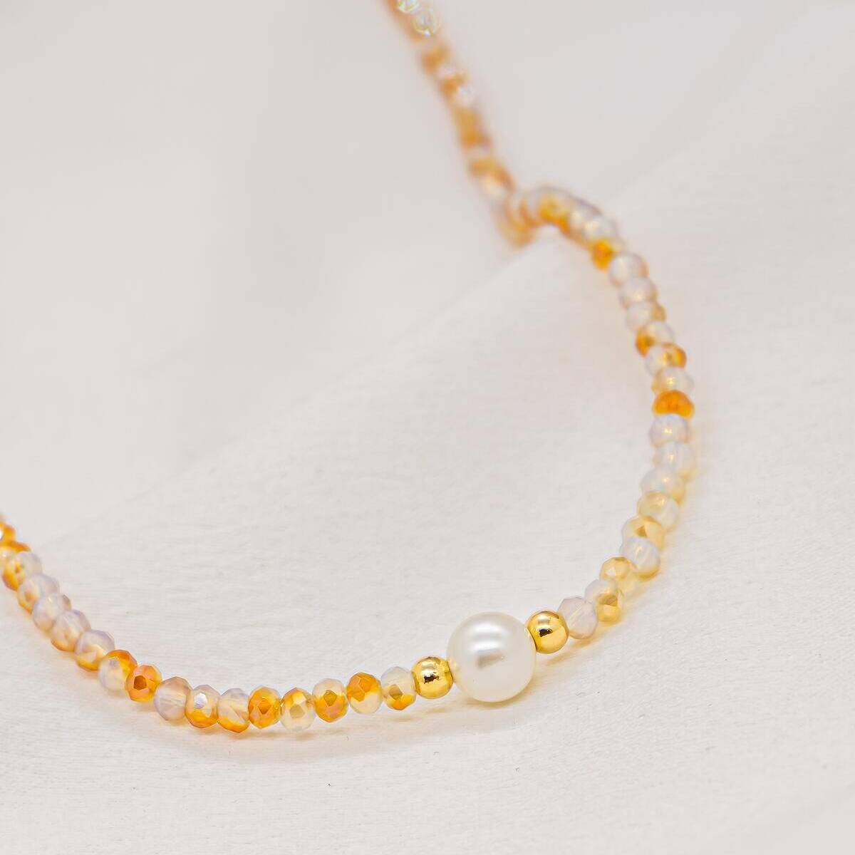 Choker necklace of small faceted beige and honey crystals with a central white pearl and gold beads