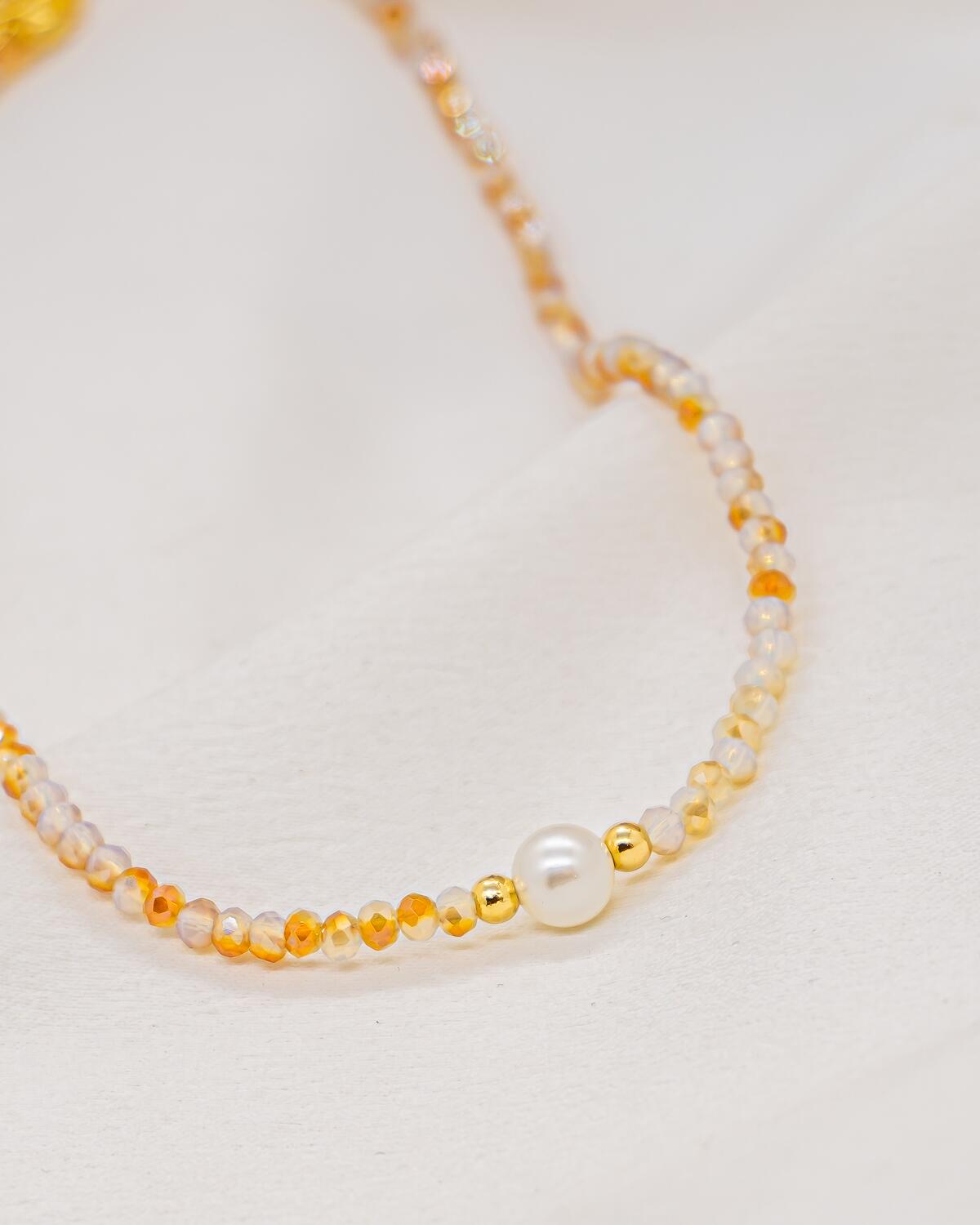 Choker necklace of small faceted beige and honey crystals with a central white pearl and gold beads