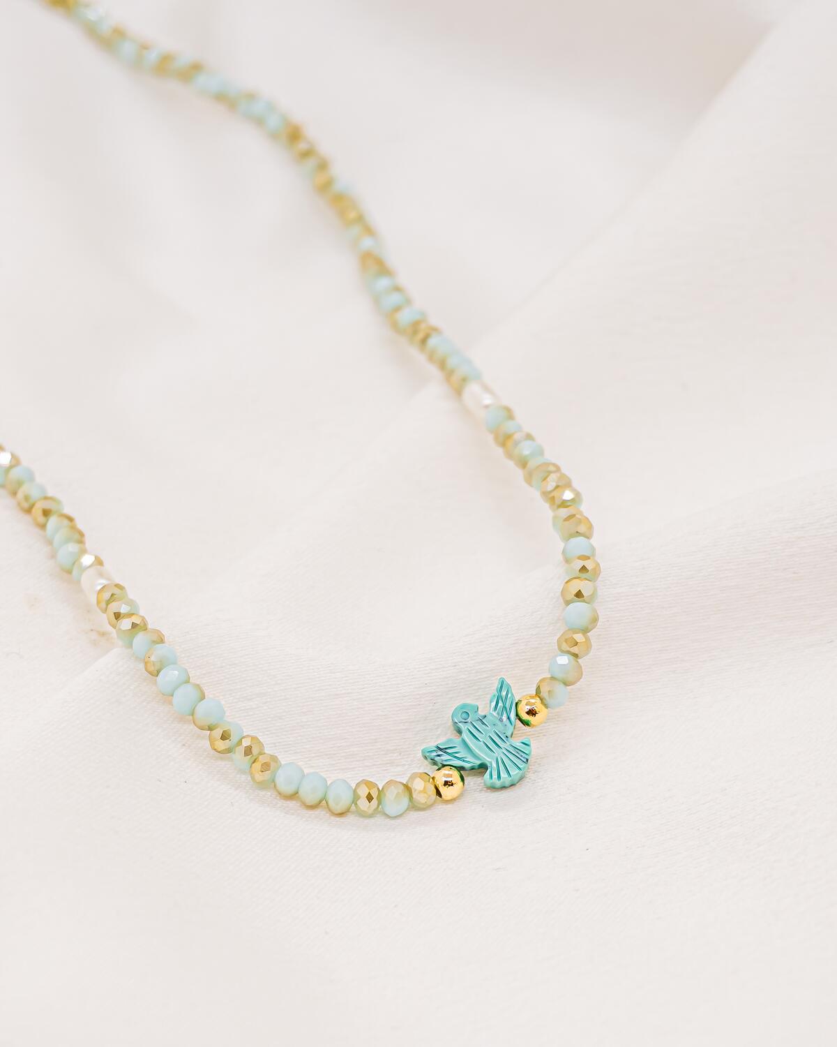 Ras-de-cou de cristaux facettés bleu pâle et dorés avec petite colombe turquoise au centre