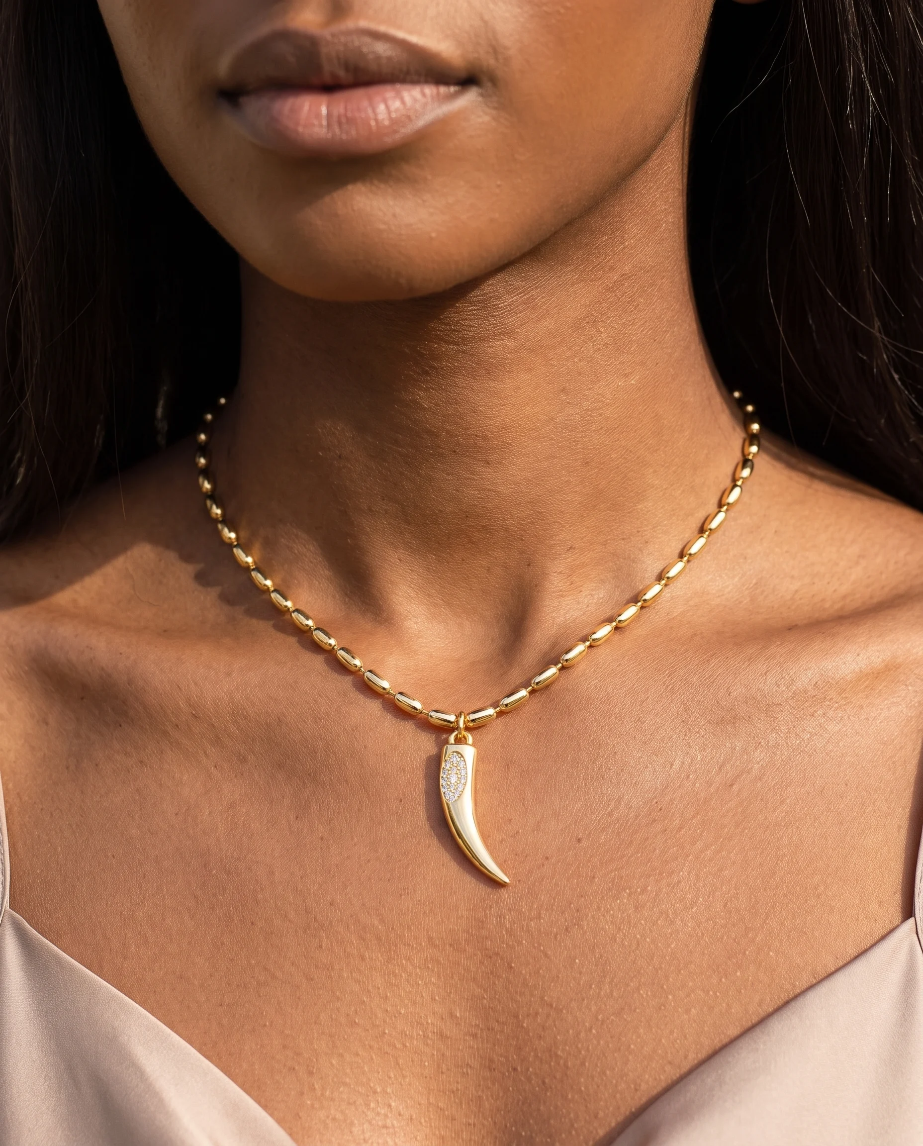 Gold rice-chain choker with saber-tooth pendant set with cubic zirconia, worn at the neck, close-up view