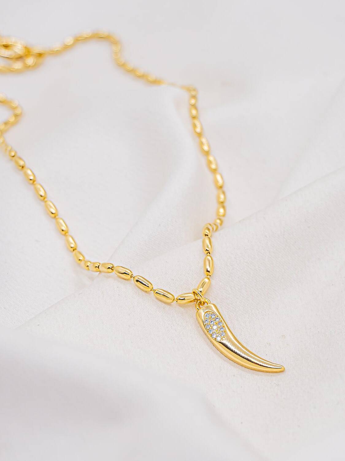Collier ras-de-cou doré à maille de grains et pendentif en corne serti de pierres claires