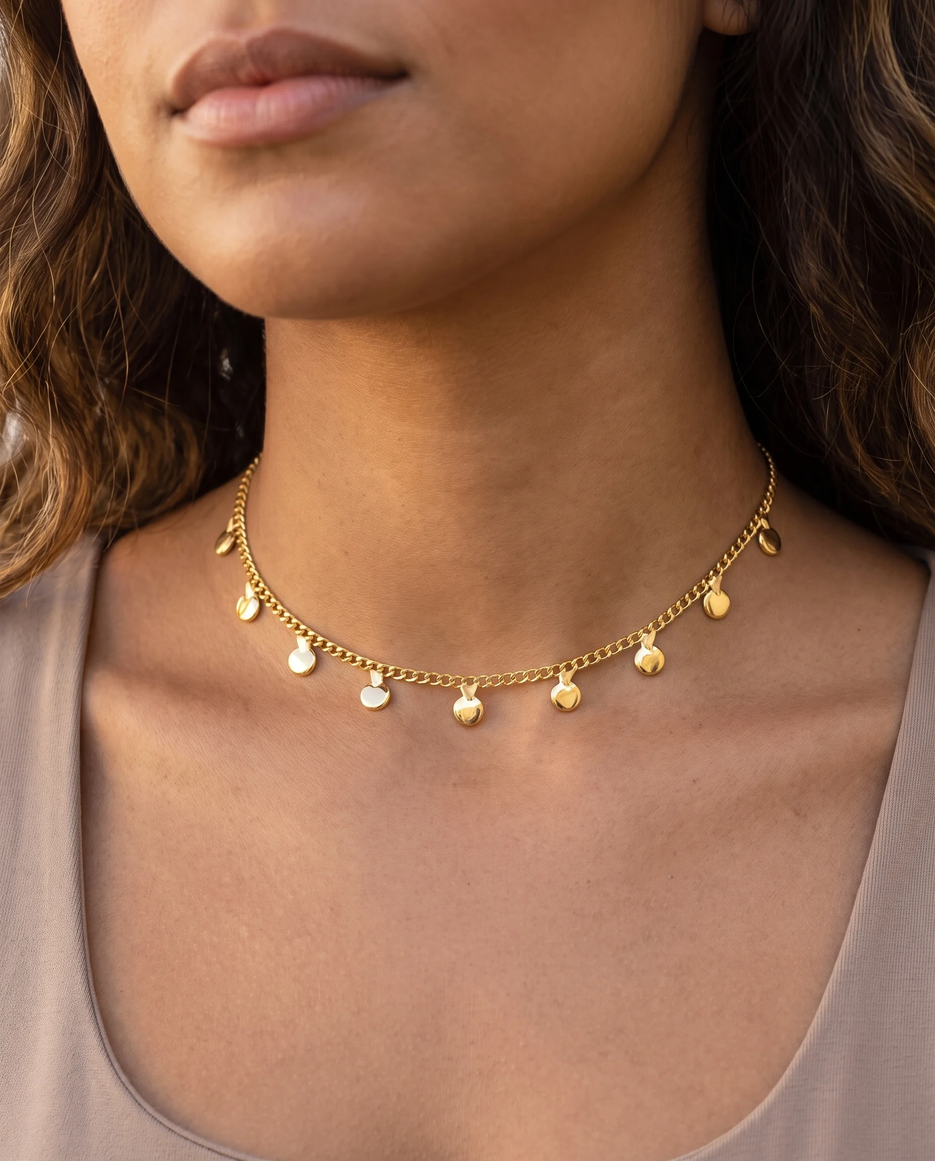 Gold choker with mini links and small round discs, worn close to the neck, close-up view