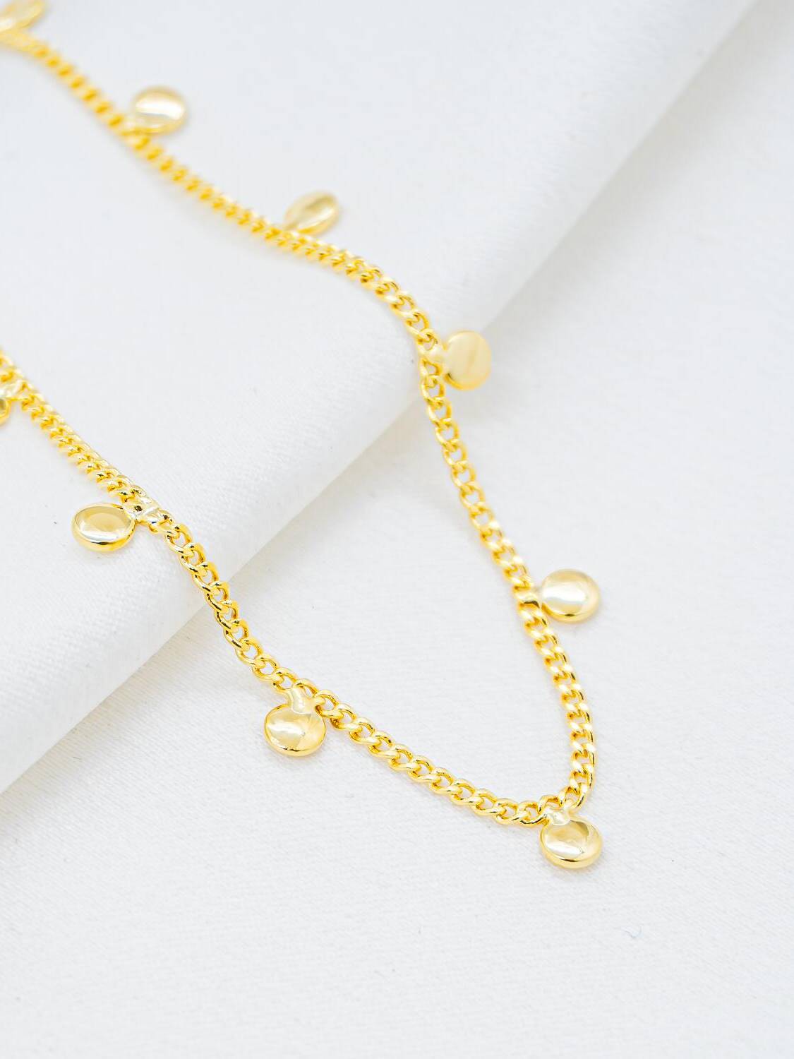 Collier ras-de-cou doré à fines mailles serrées et petites plaques rondes bombées pendantes