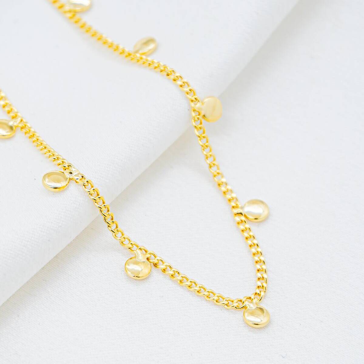 Gold chain choker with fine, tight links and small dangling domed round discs