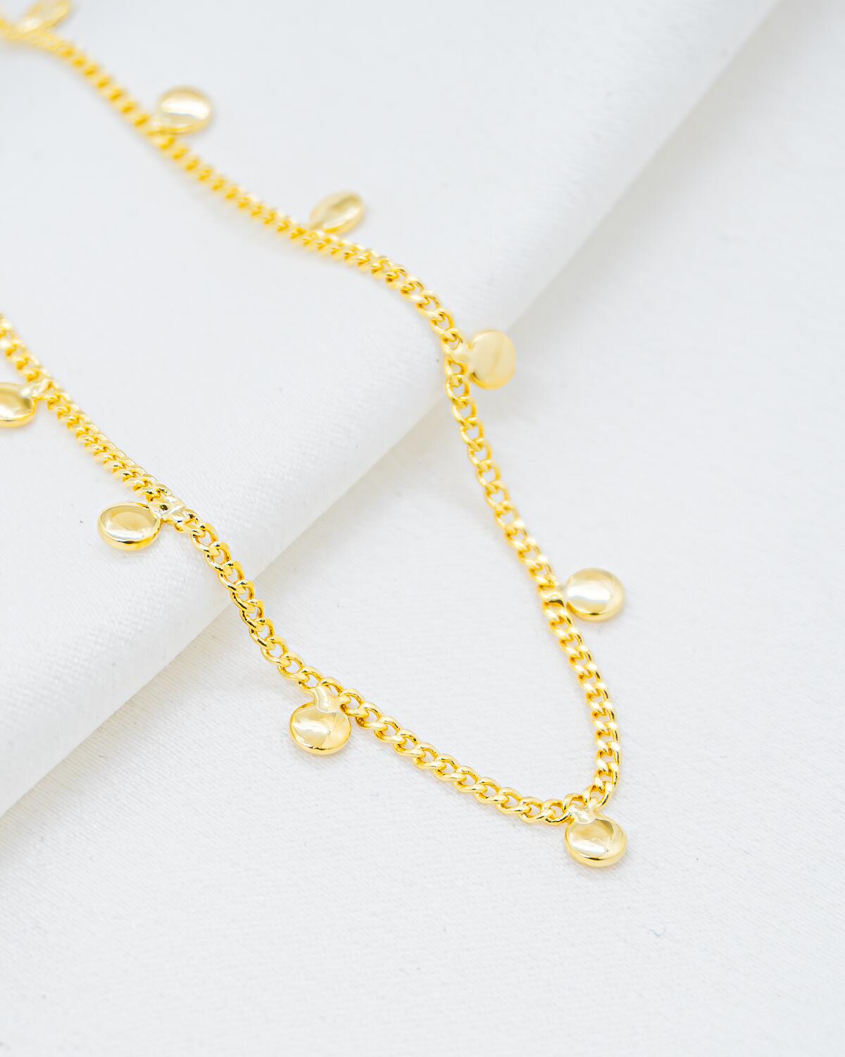 Gold chain choker with fine, tight links and small dangling domed round discs