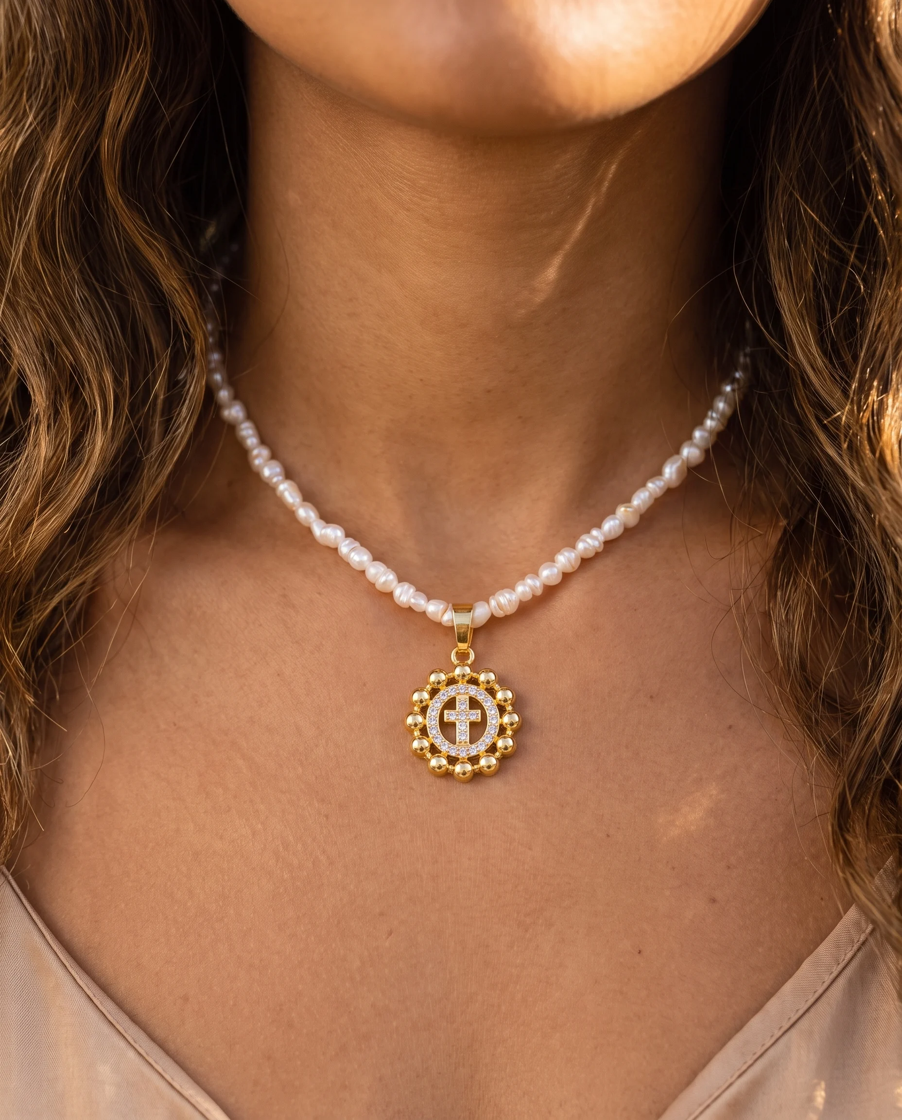 Freshwater pearl choker with small gold medallion and pavé-set cross, worn on the neck, close-up