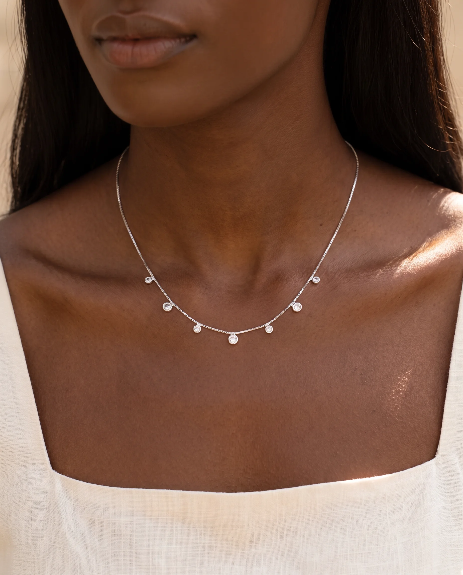 Silver necklace with sparkling stones worn below the collarbones