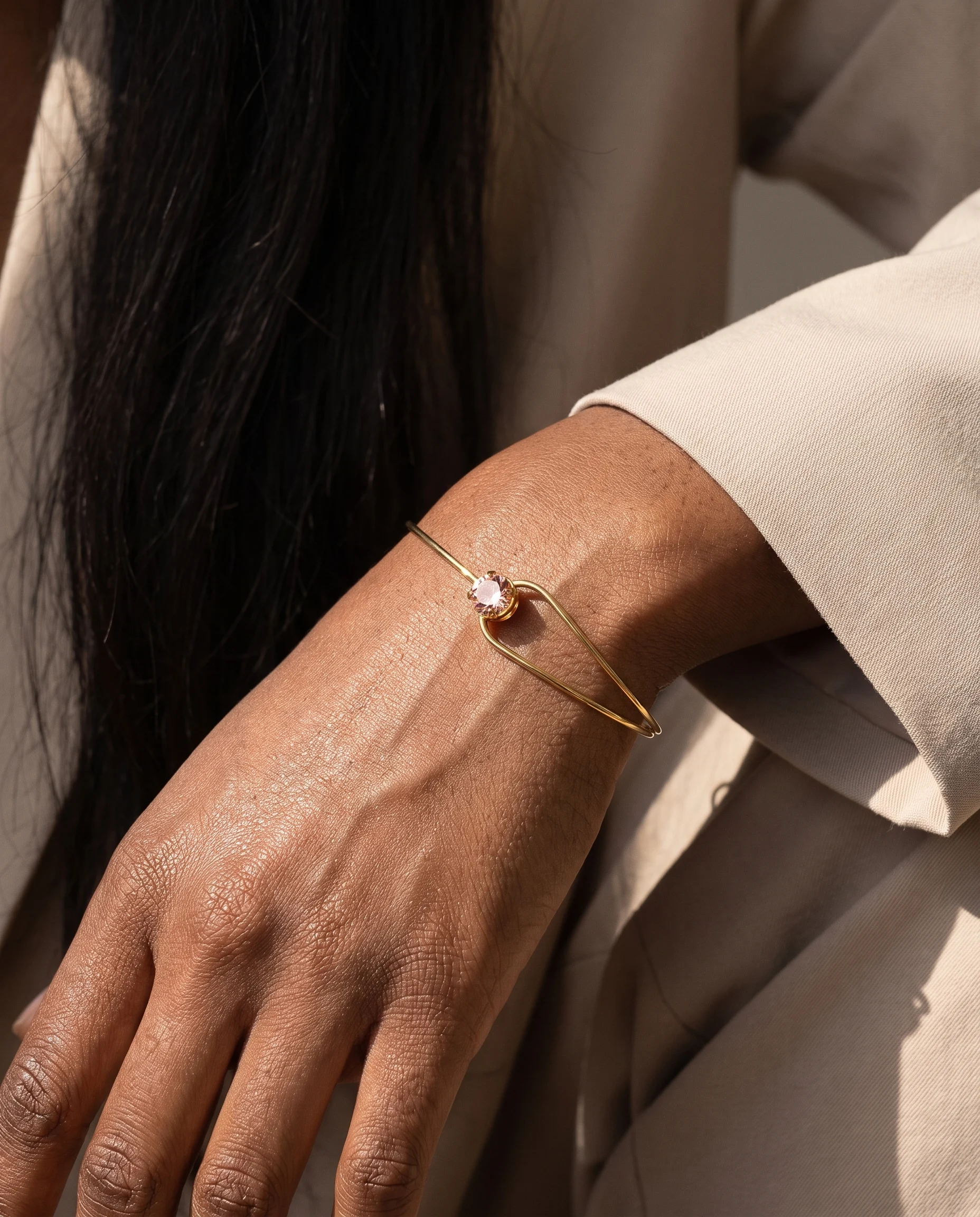 Jonc anneau fin, zircon rond rose, porté au poignet, vu de près
