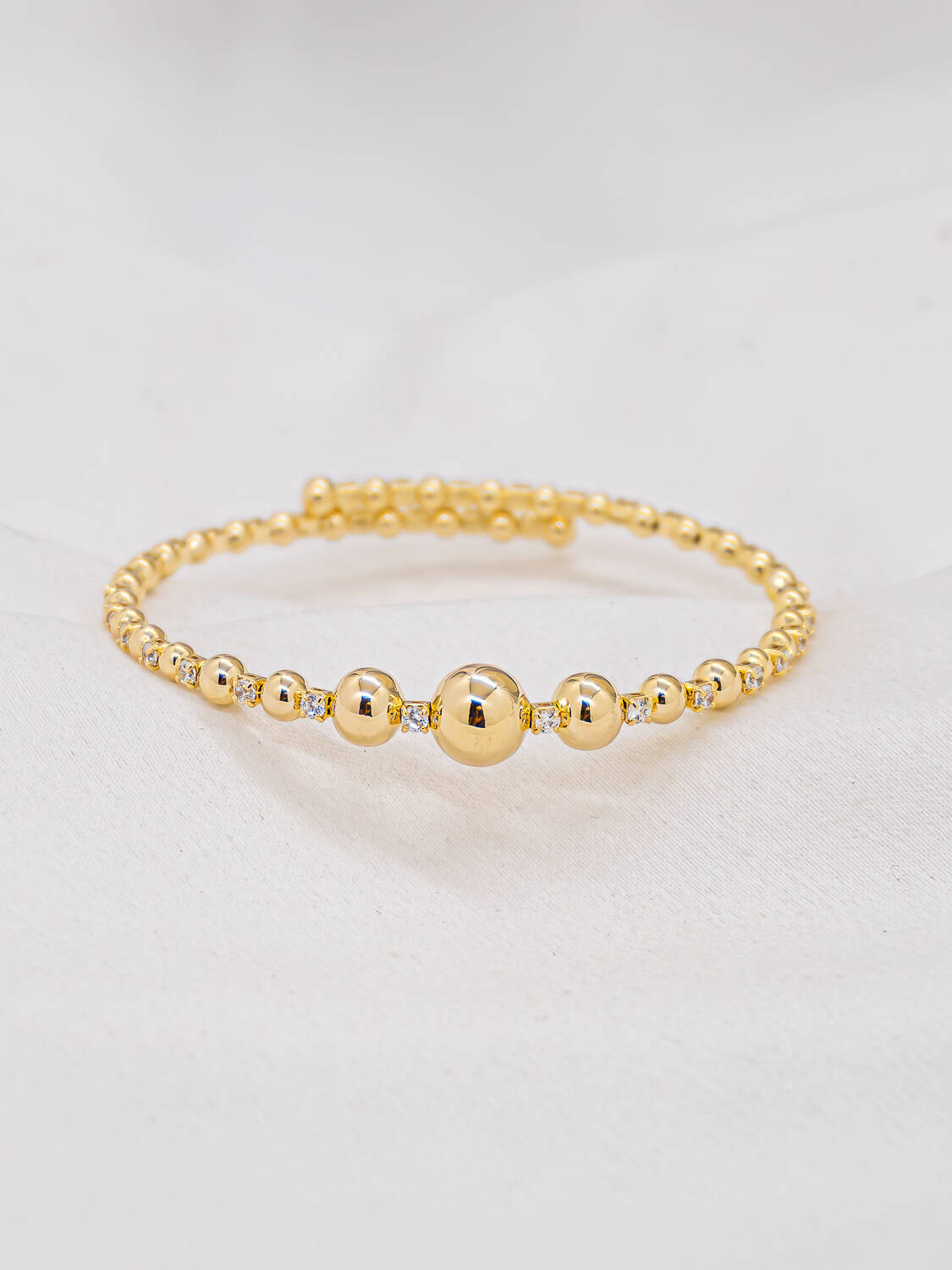 Jonc doré ajustable de boules polies alternant avec de minuscules pierres claires serties