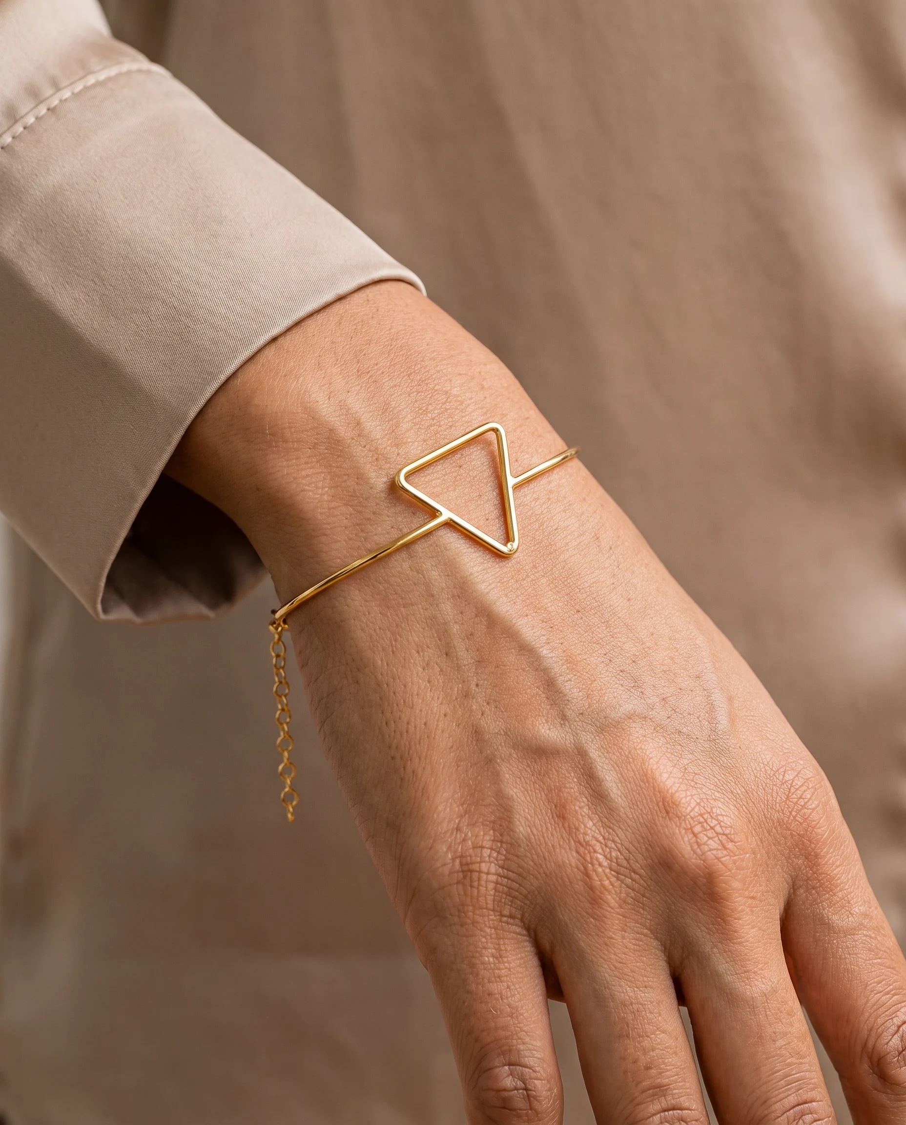 Close-up of the fine gold openwork triangle bangle worn on the wrist