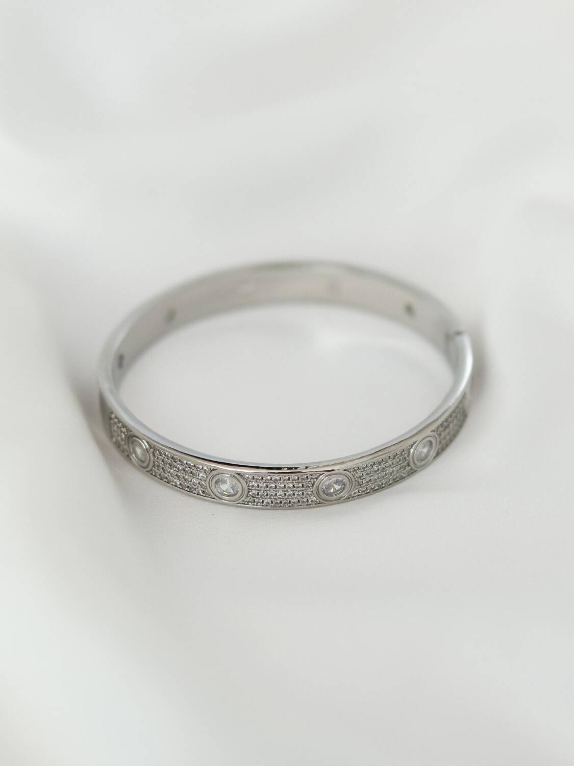 Jonc argenté pavé de petites pierres claires, avec grandes pierres ovales serties, sur tissu