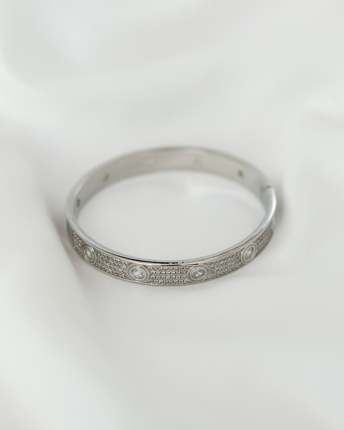 Jonc argenté pavé de petites pierres claires, avec grandes pierres ovales serties, sur tissu