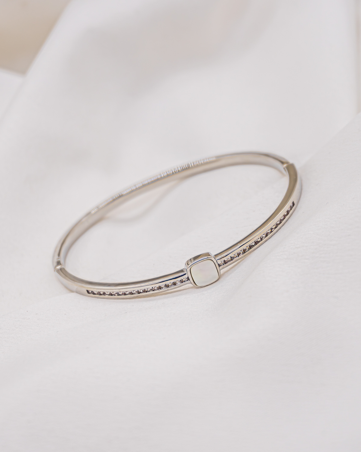 Slim silver-toned bangle with small square white mother-of-pearl and rows of tiny clear stones