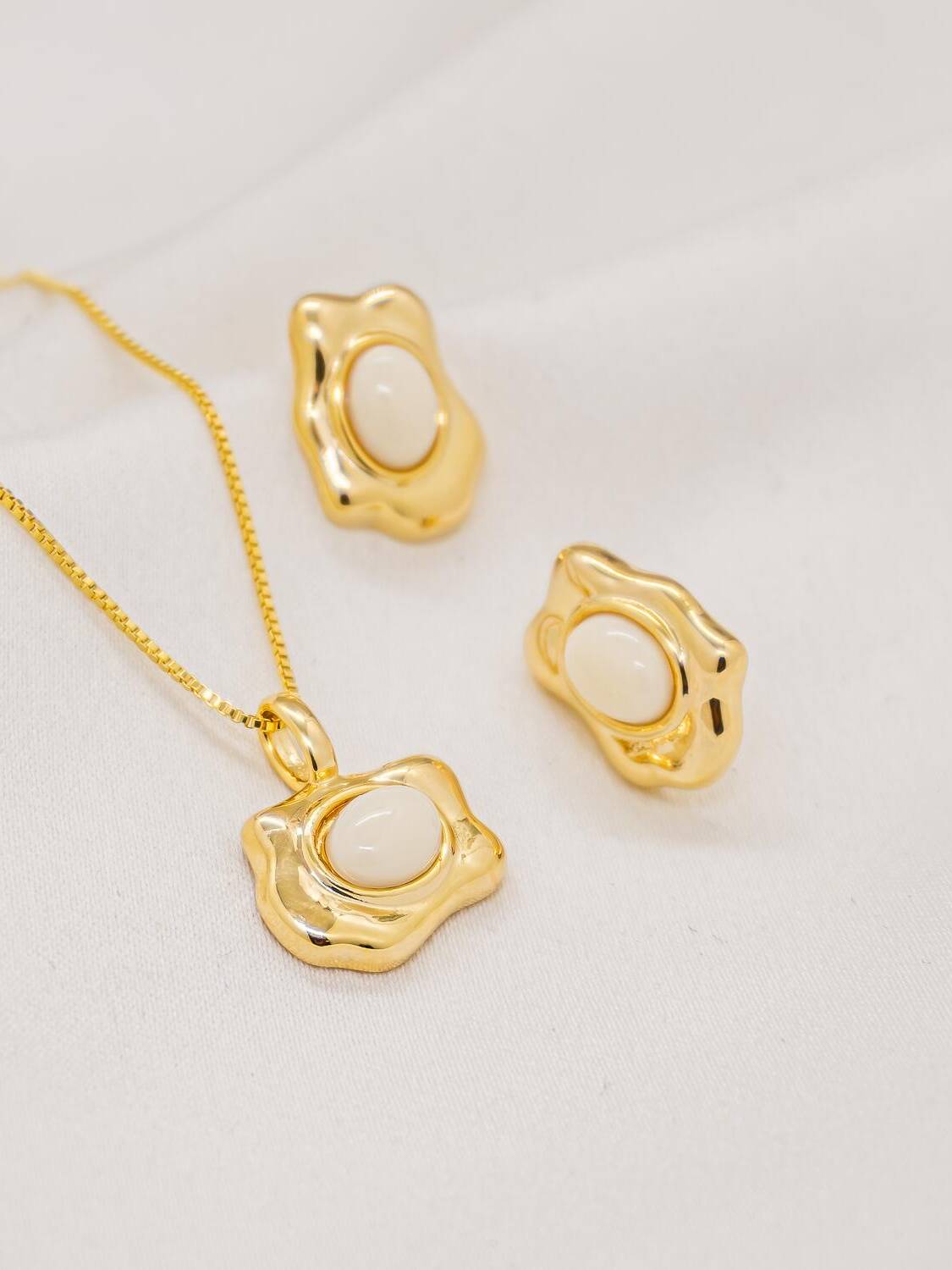 Parure dorée, pendentif et boucles d’oreilles ondulés avec pierre ovale blanc crémeux
