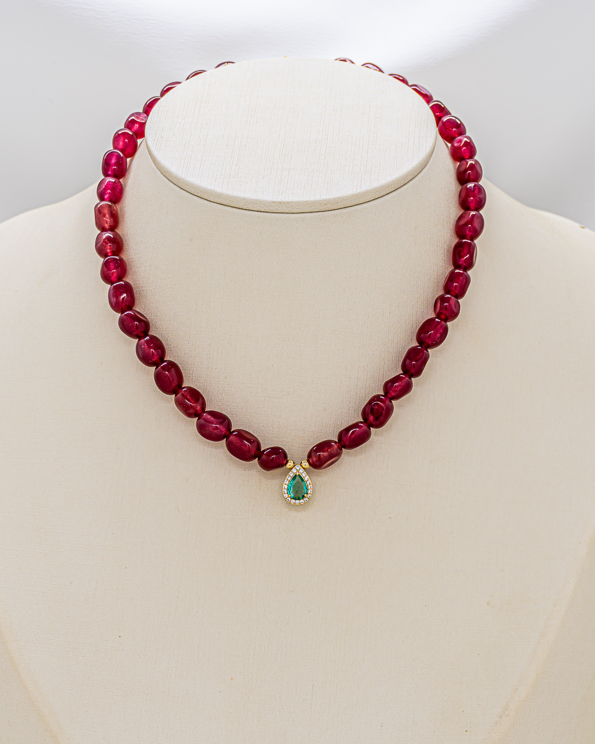 Collier de jade rouge cerise à pendentif goutte vert sur un buste blanc